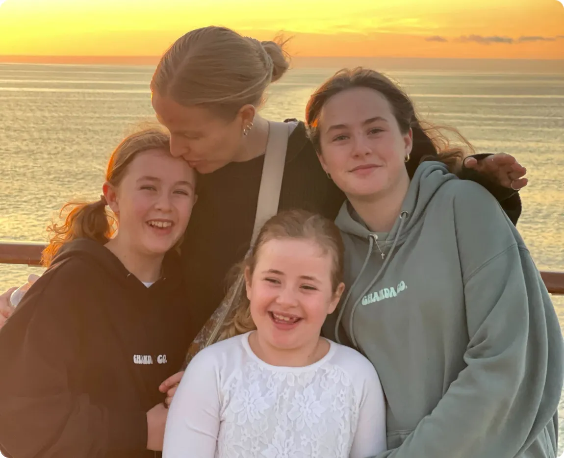 Trixie's mother and older sisters smiling in front of a sunset