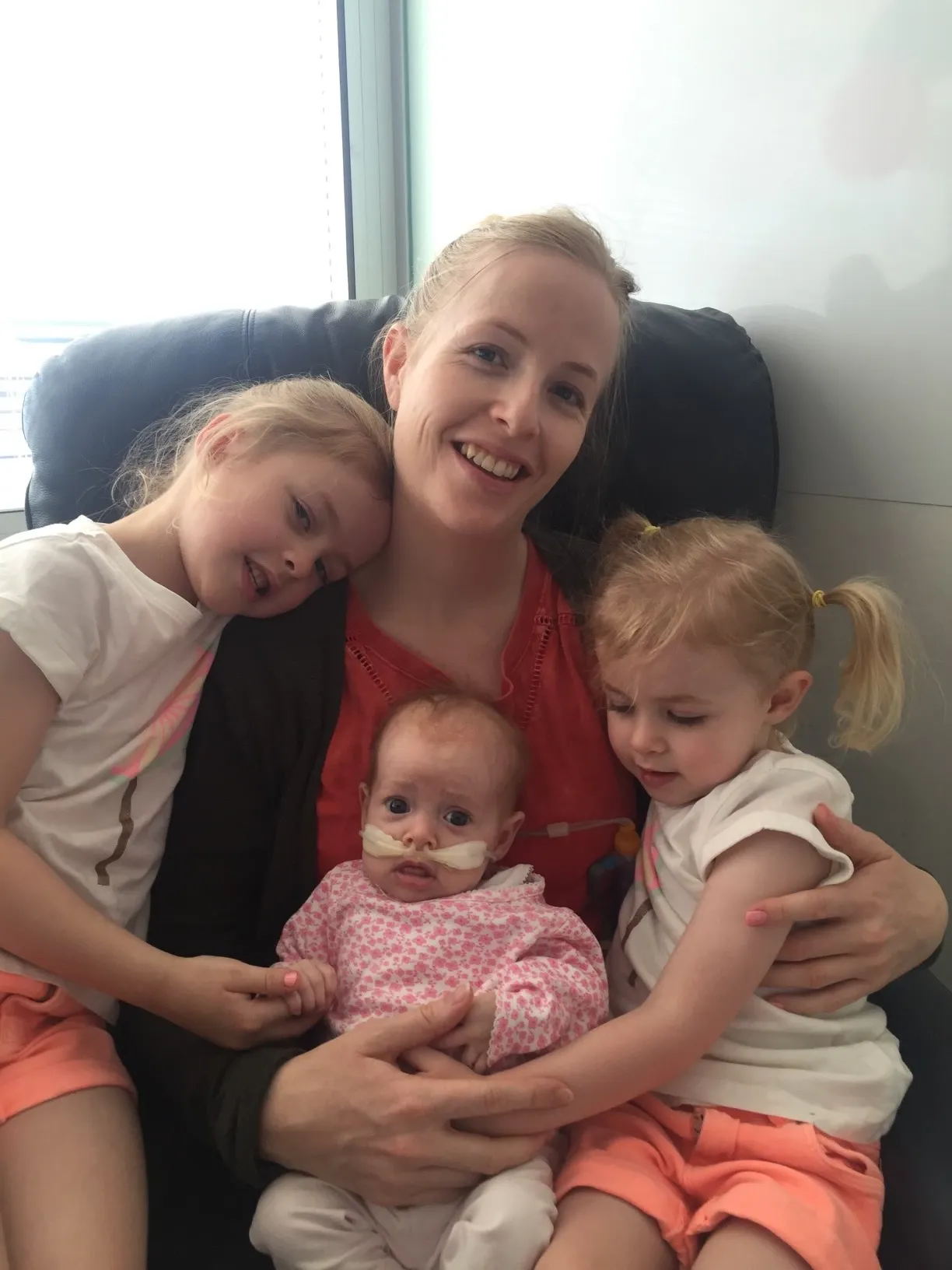 Trixie's mother smiling with Trixie and her two older sisters on her lap