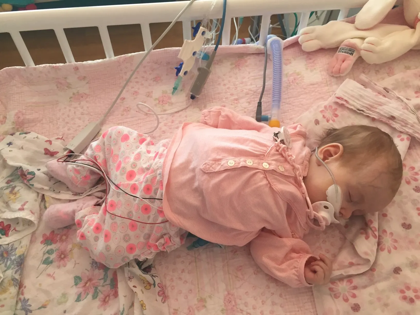 Baby Trixie asleep in her hospital cot in pink pyjamas
